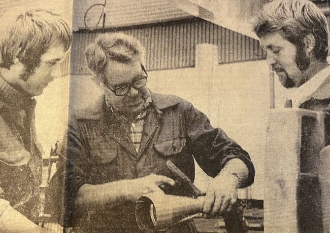 Tre medarbetare på EBV Plåt arbetar tillsammans med en plåtkomponent i verkstaden på 1970-talet.
